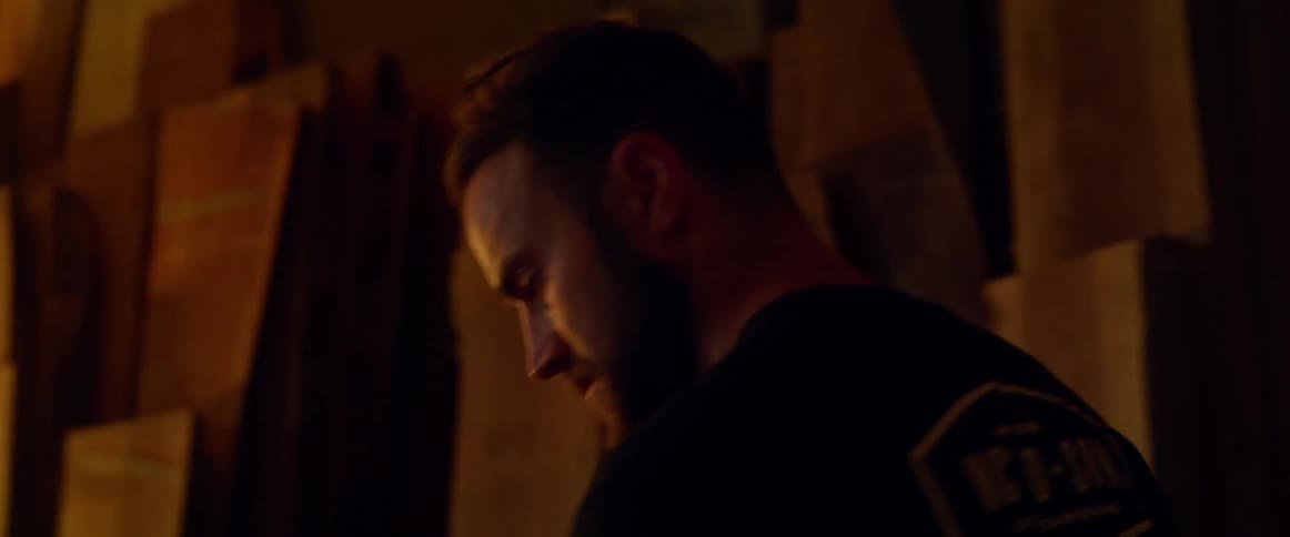 A man with a t-shirt walking in a room with boxes