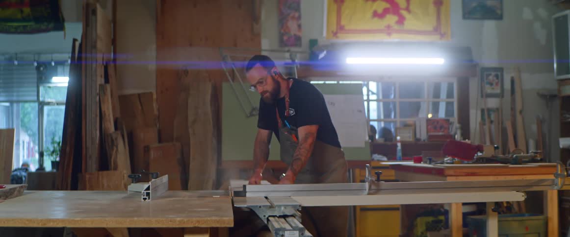 A man stands in a workshop by multiple tables