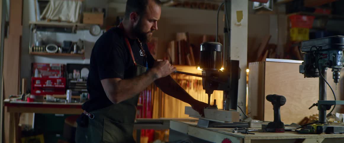A man working on a machine pressing on wood