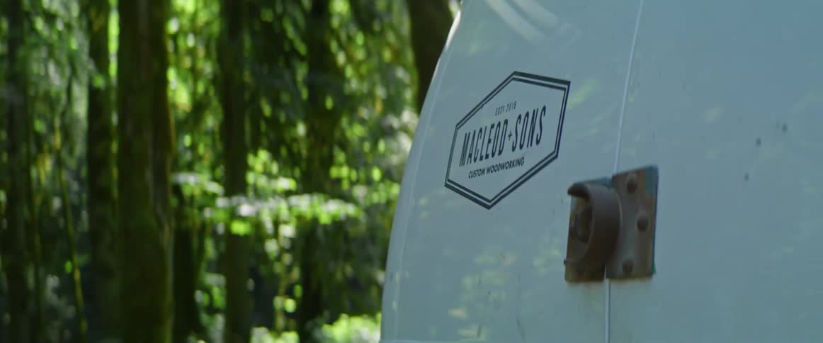 Business logo on back of work van in front of trees
