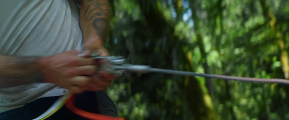 A man pulling a line from a winch into a forest