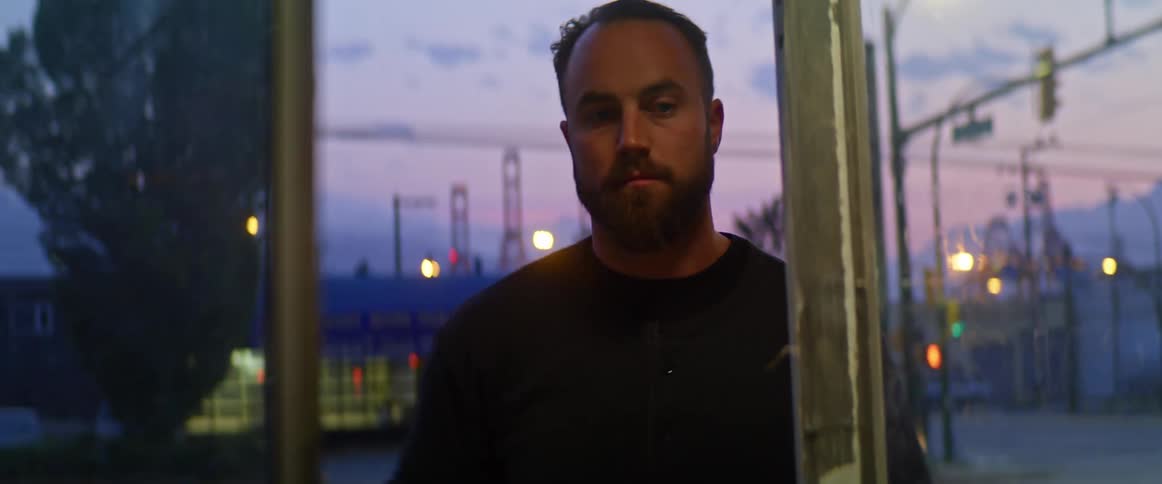 A man on a town sidewalk turns around and walks into a small store