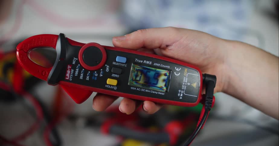 A person holds a device used to check and monitor voltage and amps of electronics