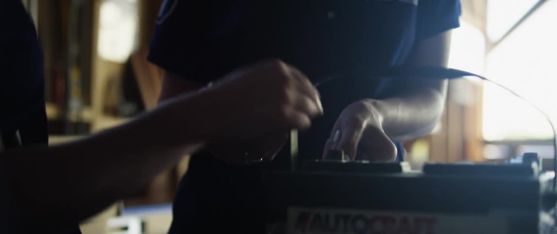 Two women looking at a car battery