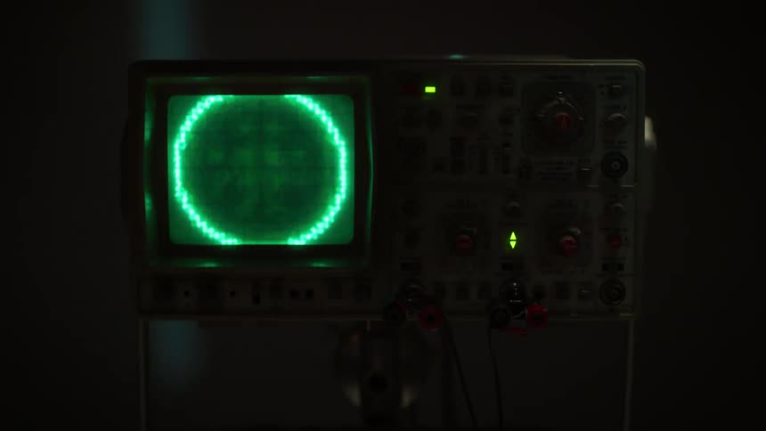 Green lights of an oscilloscope flashing on a screen in the dark