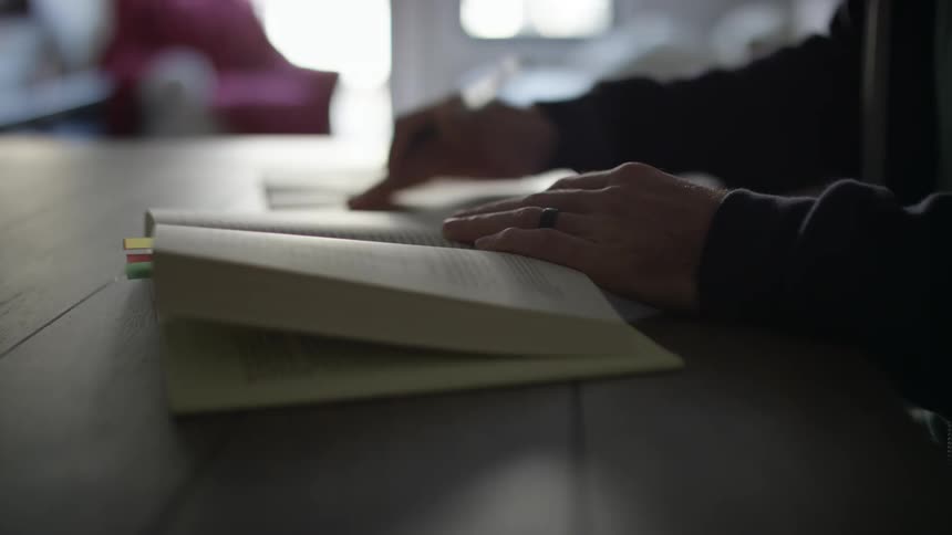 A man sits at a table and writes in a notebook