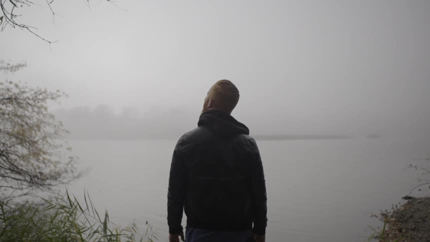 A man is overlooking a fog covered lake