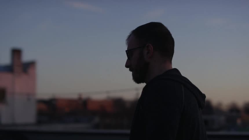 A man is walking outdoors at dusk