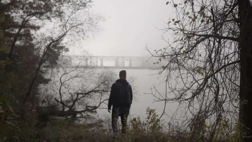 A man walks over to the water from the grass