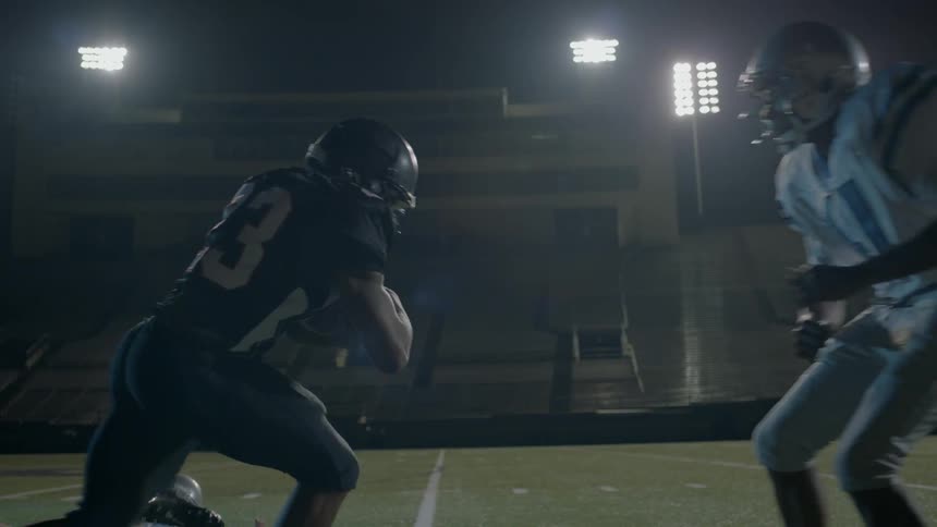 A football player holding a ball runs into players on the opposite team