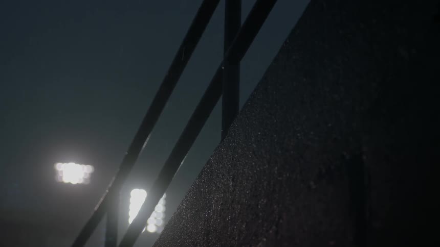 Close up of a railing in a stadium with lights at night