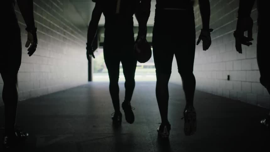 Football players walk through a stadium hallway