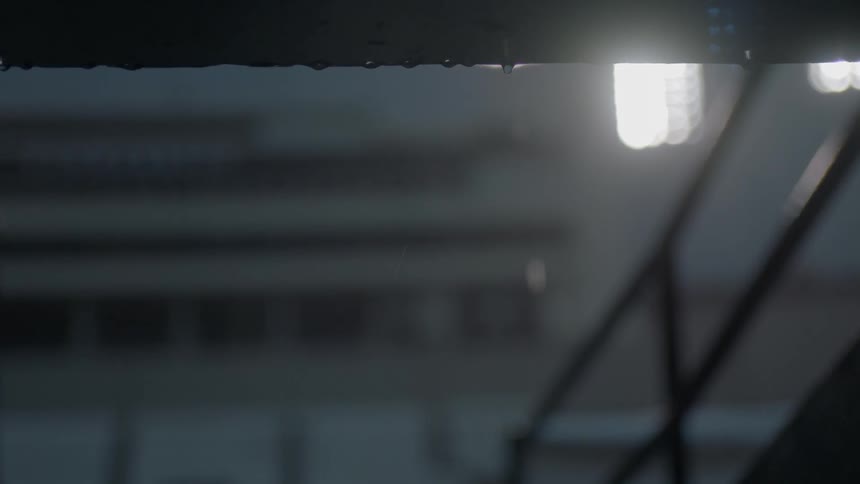 Water is dripping from a railing in a dark area