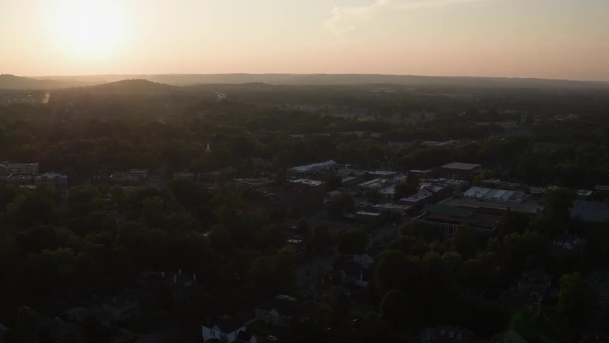 The sun rises over a wooded city