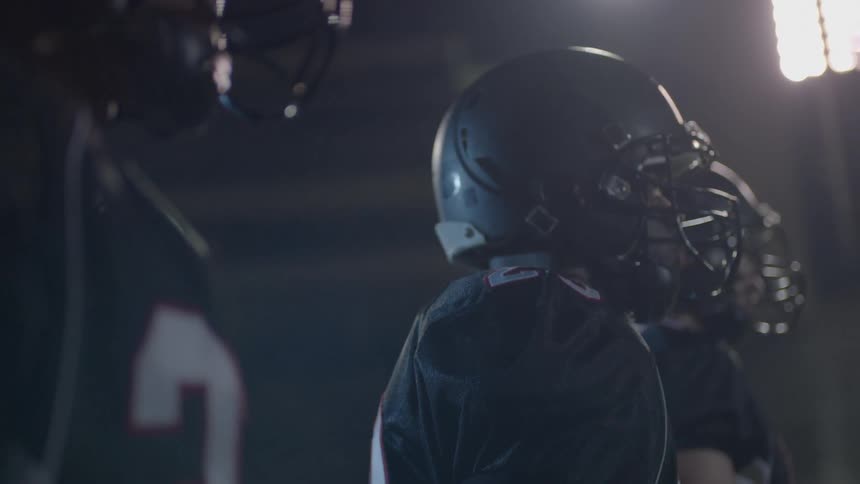 A football team walks in a brightly lit stadium