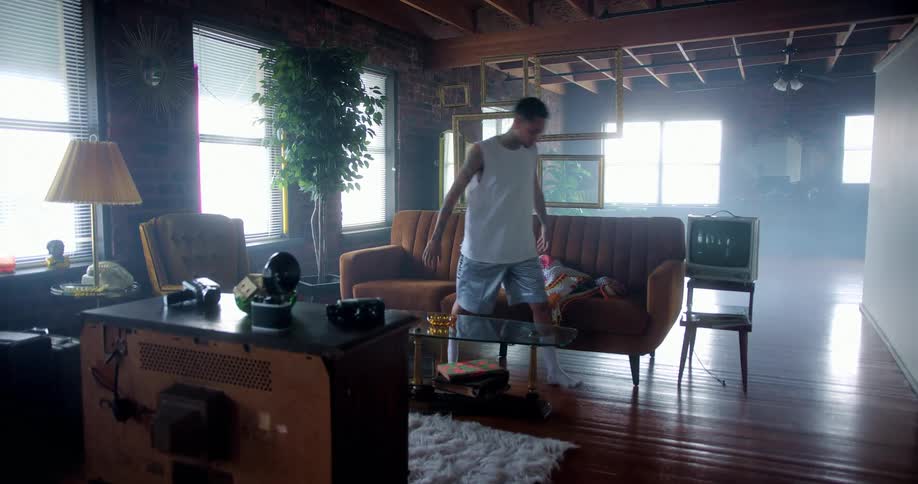 Tattooed man sitting on a sofa stands up and walks out the living room at home