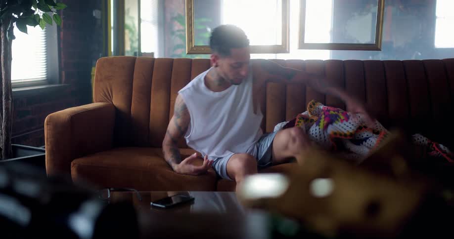 A man is sitting on a couch during the day