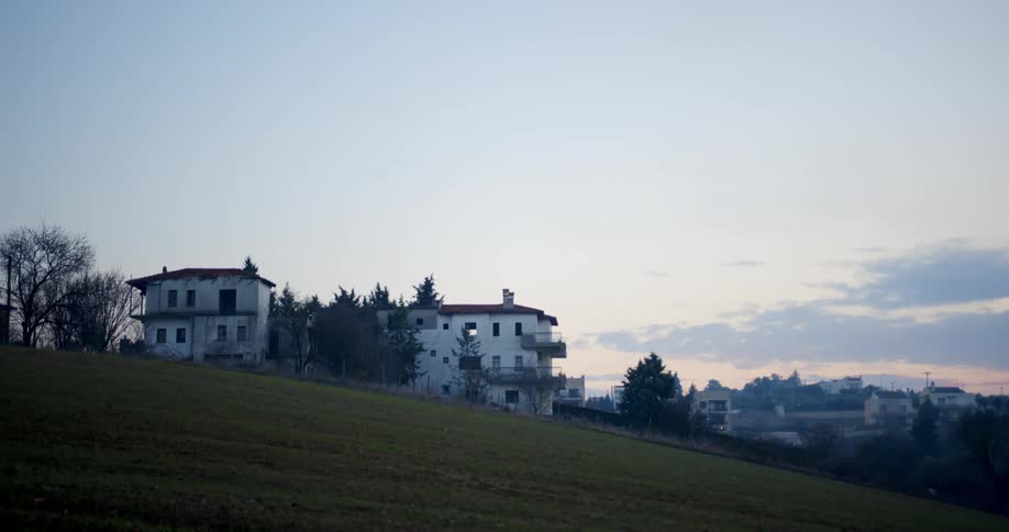 White apartment buildings sit along the slope of a freshly mowed lawn