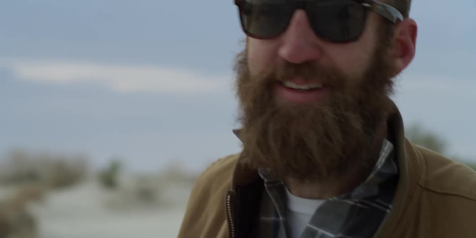 A bearded man in sunglasses smiles