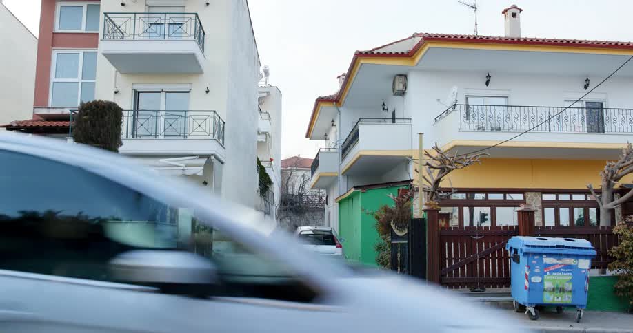 Car drives along street past apartment buildings