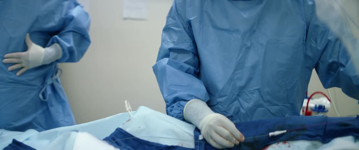 A surgeon with glasses mask and gloves in a hospital operating on a person