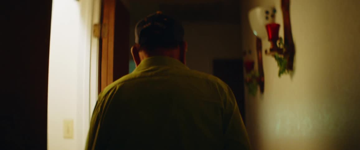 Man walks forward down corridor passing open doors