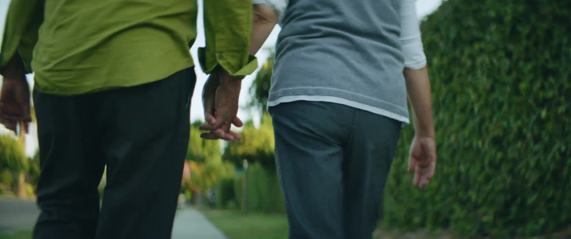 A man and woman walking down a sidewalk holding hands