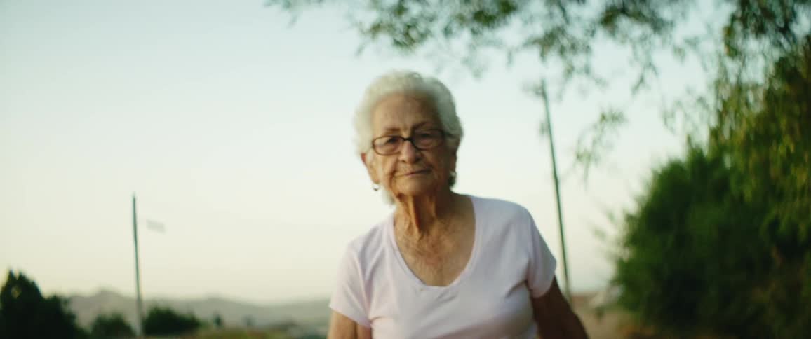 An elderly woman is walking outdoors in spring
