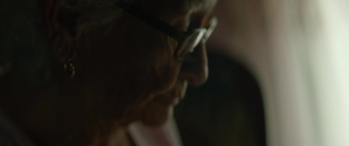 An elderly woman is standing inside a house