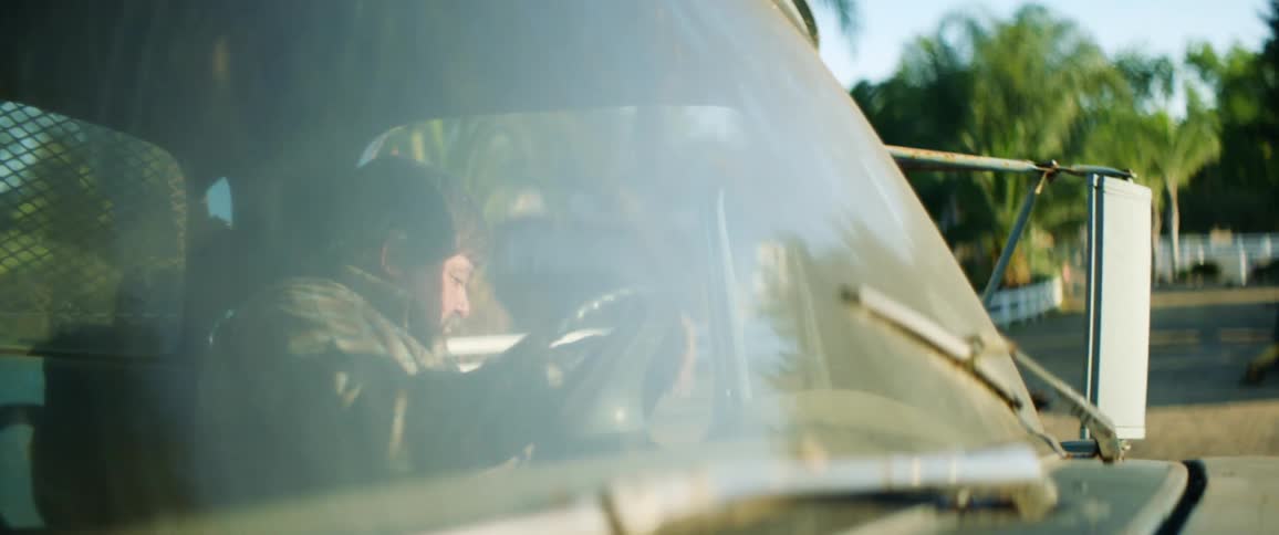 A middle aged man exits a pickup truck on a sunny day