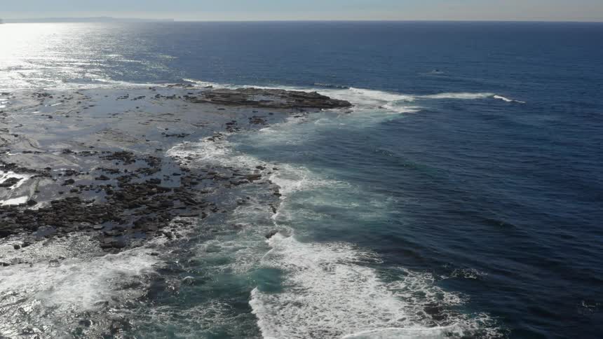 Flying over an ocean with waves crashing