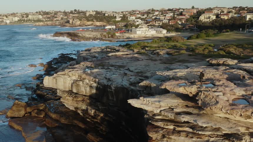 A woman walking on cliffs above the ocean