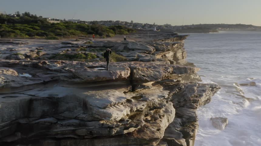 Man stands on cliffs overlooking ocean