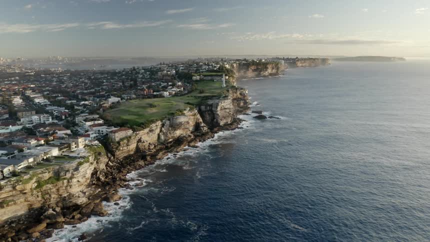 Flying over cliffs at the edge of a city at the ocean