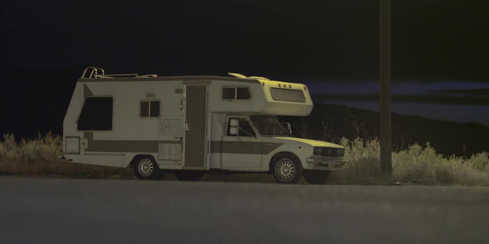 An rv is parked on a street at night