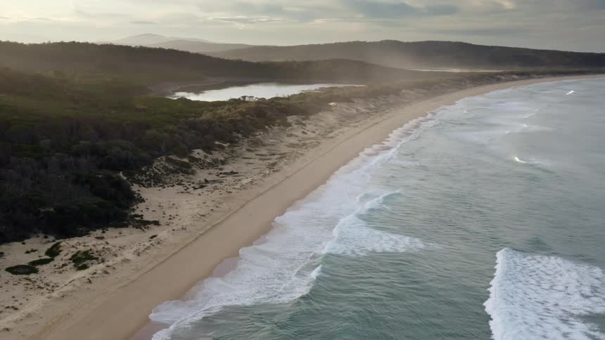Ocean waves wash into a long sandy beach in the wilderness during the day