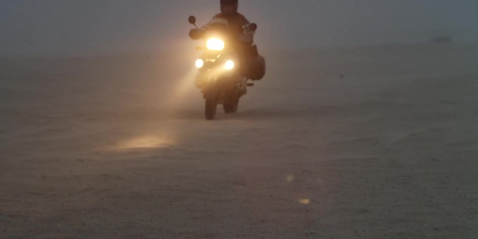 Two people riding motorcycles off road on a foggy evening