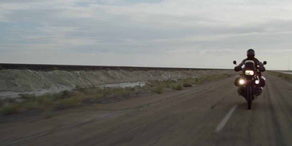A motorcycle is riding down a road on a cloudy day