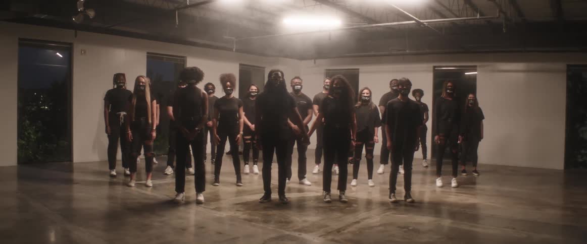 A group of people in black stand together in the room