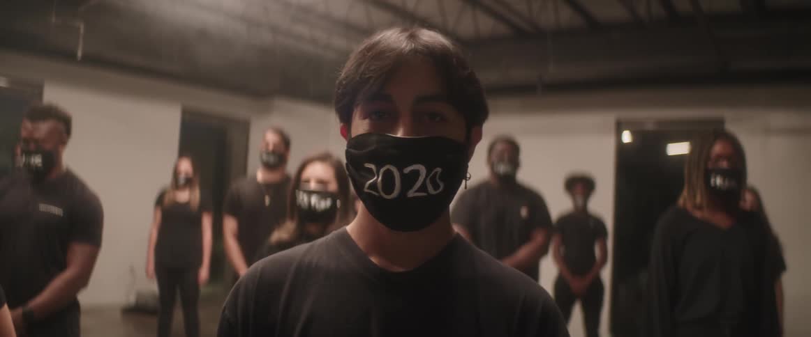 Group of people stand in a room wearing black face masks