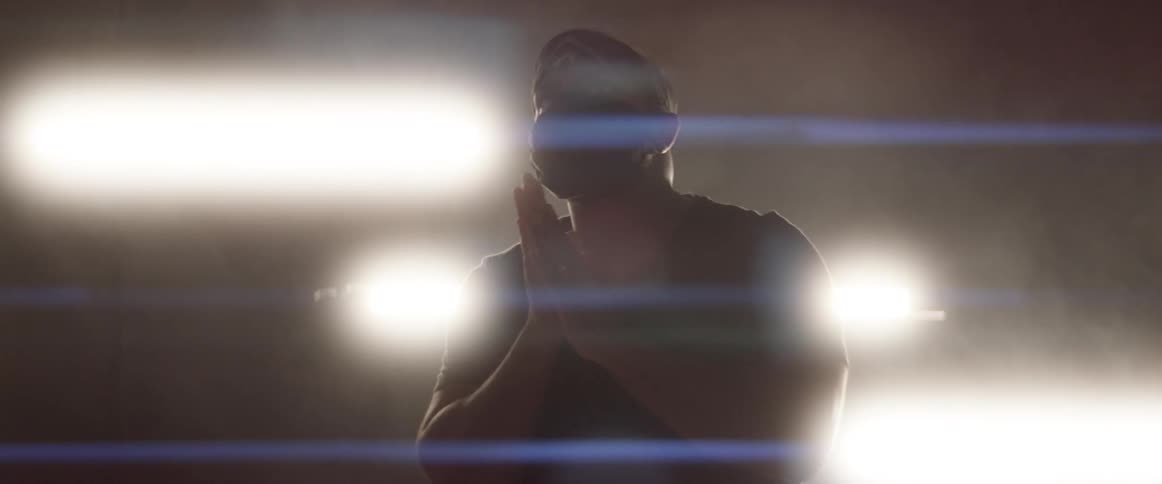 A man with a bandana and mask standing with lights in the background
