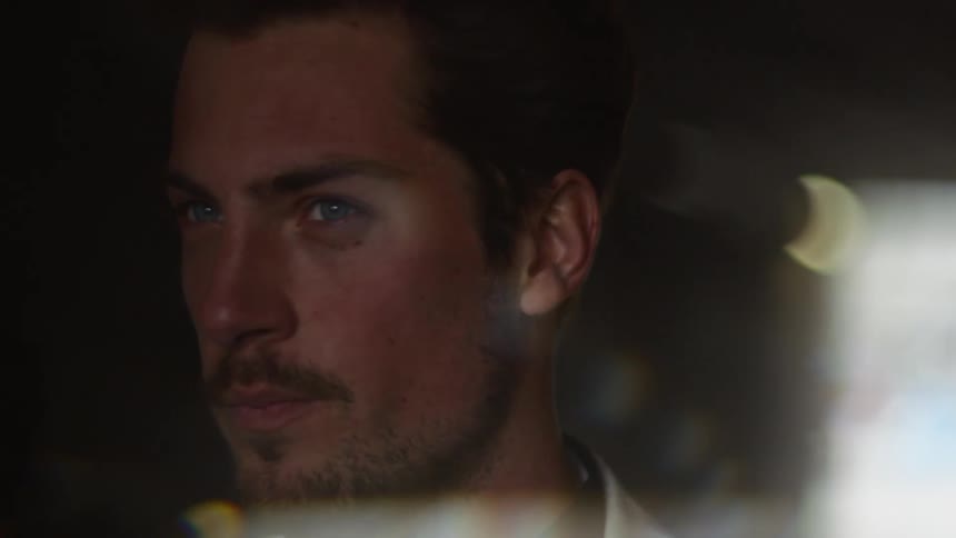 A man stands next to a window and turns his head to look outside