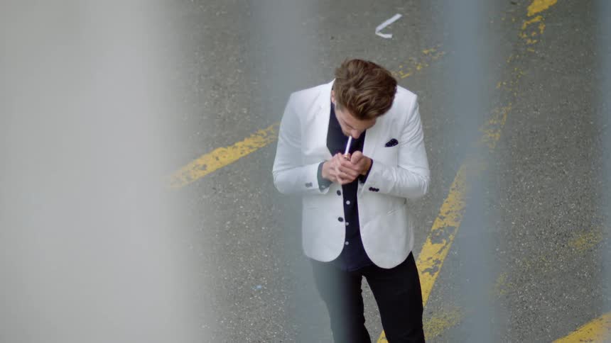 A man standing outside lights a cigarette