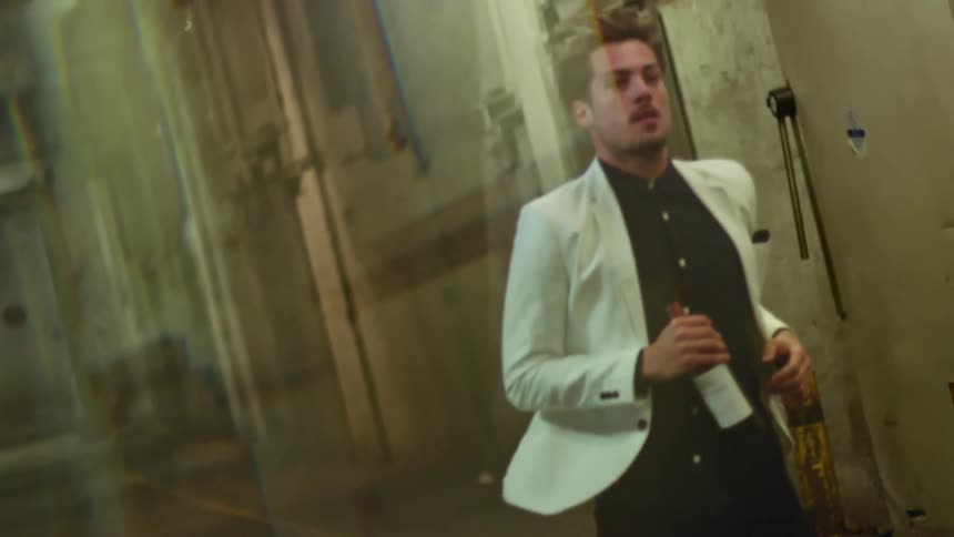 A man with a white blazer jogging with a bottle in his hand