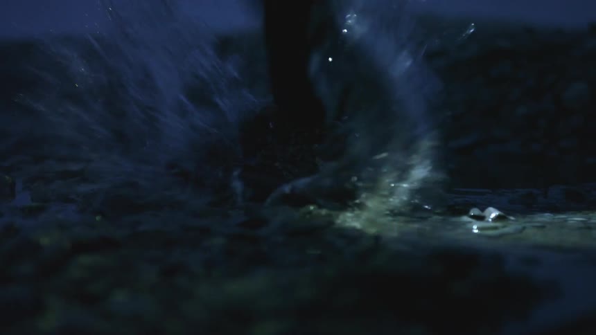 A person walking outside at night steps in a puddle