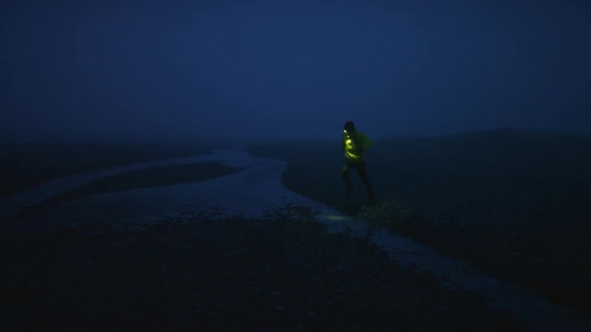 A man jumps over a stream at night