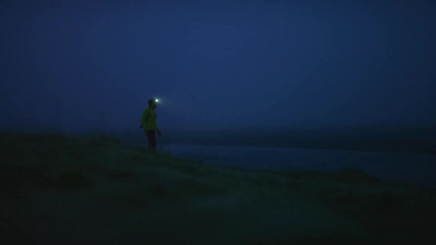 A man hiking at night with a headlamp on