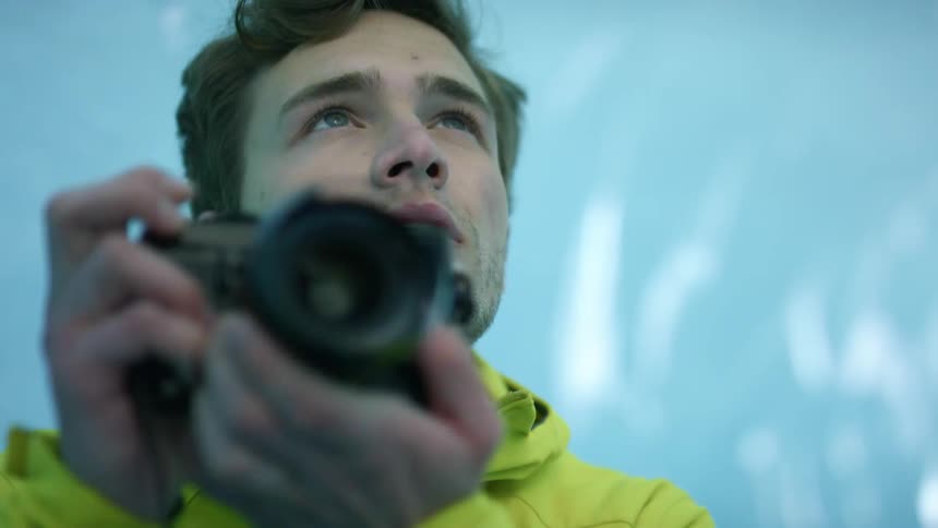 A man is taking photos in a tunnel of ice