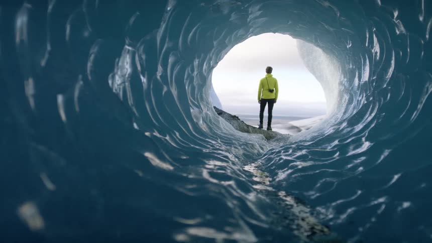 A man standing at the end of an ice cave