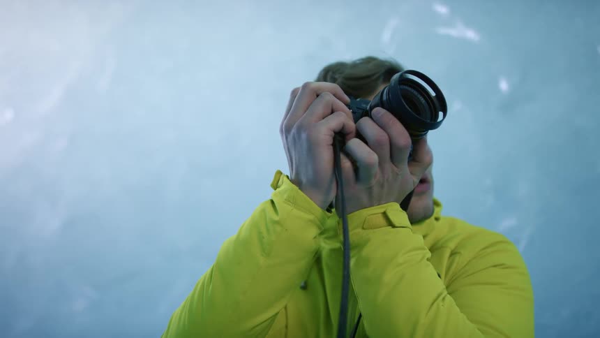 A man with a camera and a hoodie in an ice tunnel